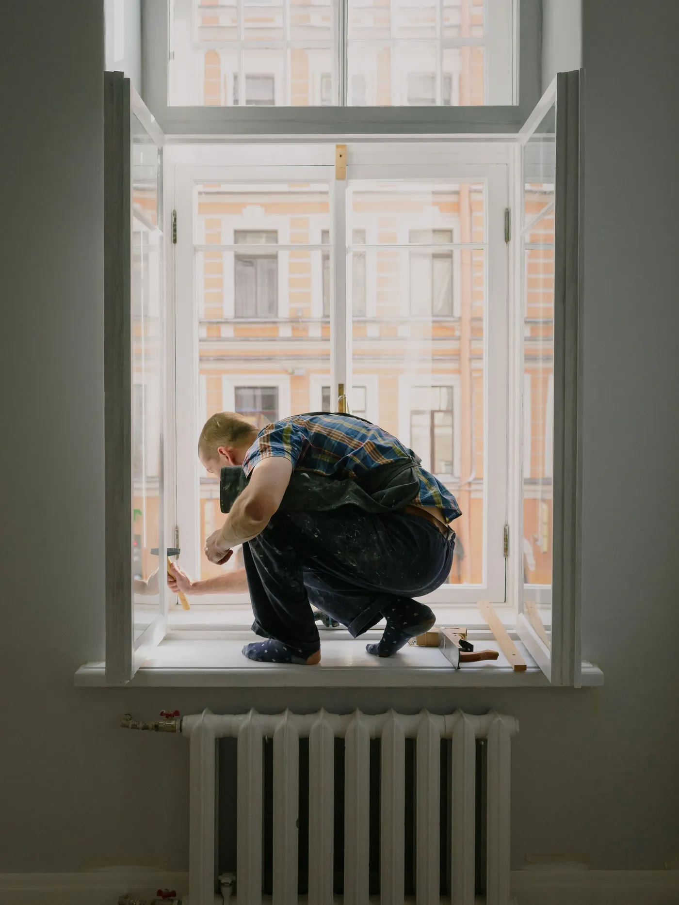 Handwerker repariert ein Altbaufenster in einer Wohnung