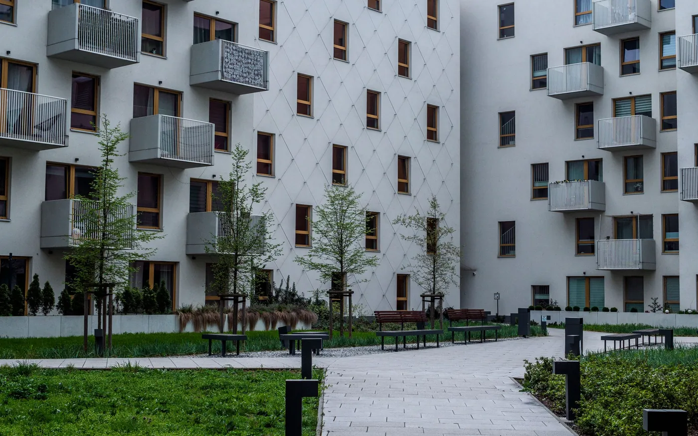 Innenhof einer Wohnanlage mit Bänken, Bäumen und Balkonen